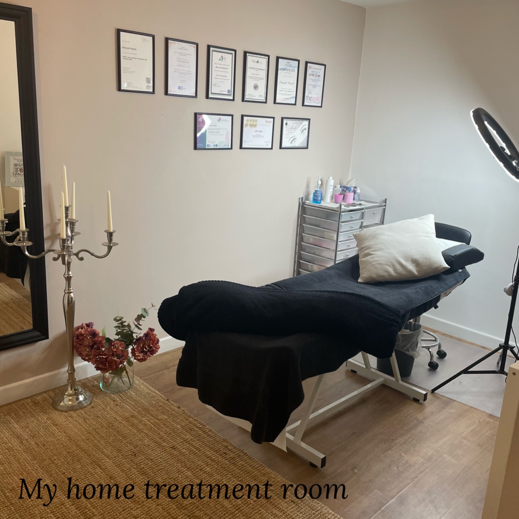 Hannah's home treatment room: a black treatment couch, framed certificates on the wall and a ring light